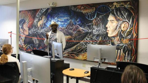 Terrance Gray standing in front of mural in electronic music classroom